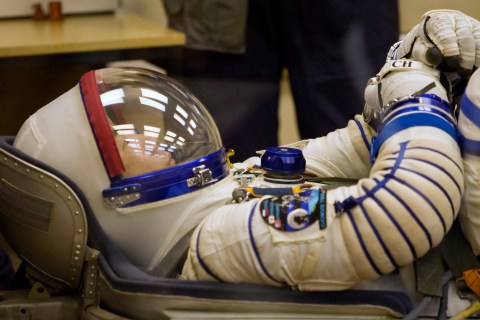Japan Aerospace Exploration Agency astronaut Soichi Noguchi waits while ground personnel check his space suit at the Baikonur cosmodrome