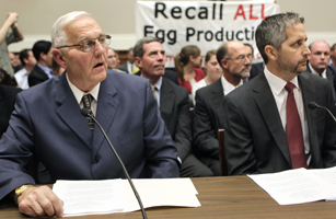 Protesters hold a banner as Austin DeCoster, owner of Wright County Egg, and his son Peter testify before the House Oversight and Investigations Subcommittee hearing in Washington