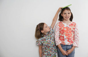 Girl Measuring Big Sister's Height
