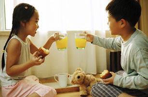 Young boy and girl toasting with glasses of orange juice