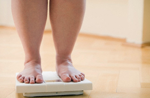 Legs of Overweight Woman Checking Her Weight on Bathroom Scales