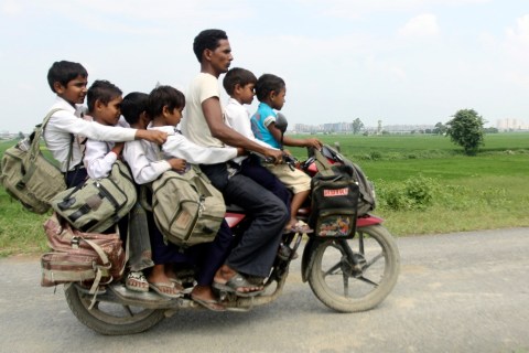 A man rides a motorcycle carrying six children on their way back home from school at Greater Noida in the northern Indian state of Uttar Pradesh