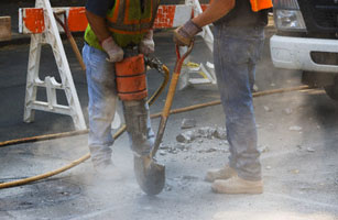 Construction workers using jackhammer and shovel