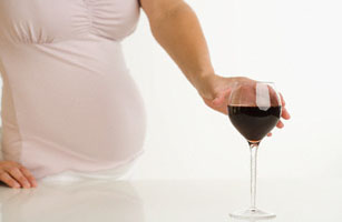 Pregnant Woman Reaching for Glass of Wine