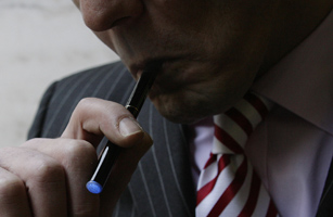 Managing Director of The Electronic Cigarette Company smokes an electronic cigarette as he poses for the photographer in London