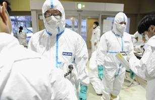 Police who have finished measuring radiation are screened for radiation contamination in Kawamata