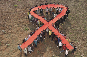Students form a red ribbon during an HIV/AIDS awareness rally ahead of World AIDS Day in Hanshan county