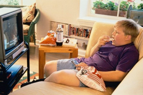 Boy eating junk food in front of TV