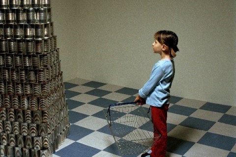 Girl standing next to stack of canned food