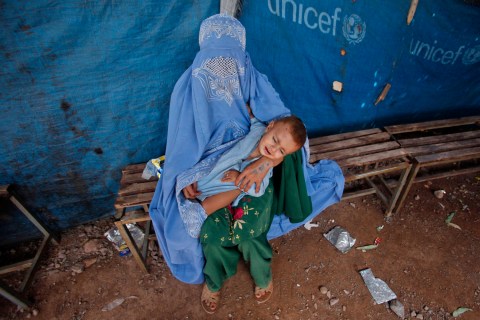 An Afghan refugee woman waits her turn to receive a drop of polio vaccine for her child at the United Nations High Commissioner for Refugees (UNHCR) supported Jalozai camp on the outskirts of Peshawar