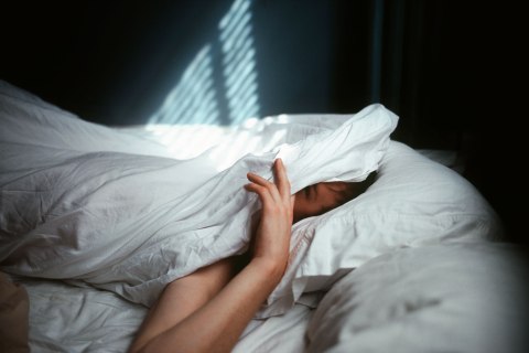 image: Man peeking out from sheets