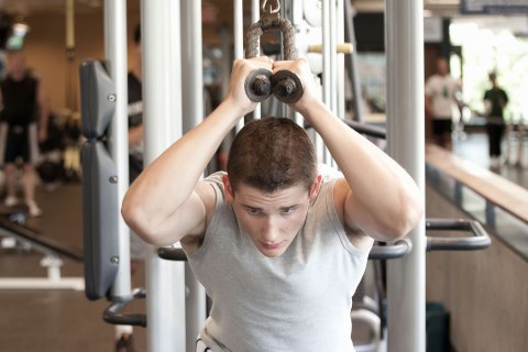 Young man lifting weights in gym