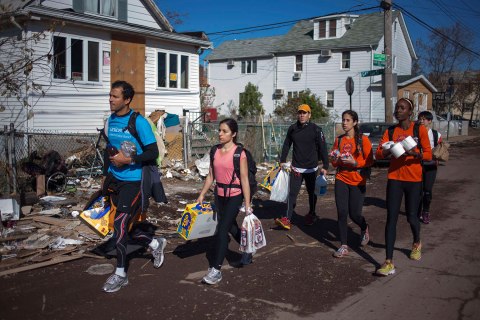 image: New York City Marathon runners carry relief supplies through a damaged neighborhood in Staten Island, N.Y., Nov. 4, 2012. 
