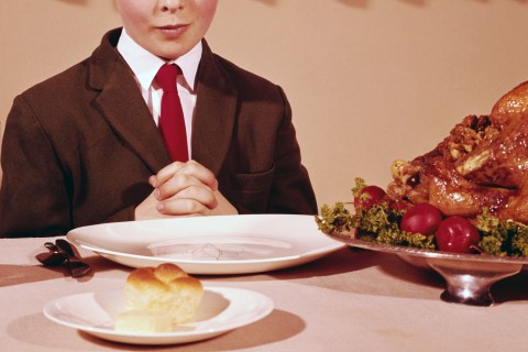 image: A child prays during Thanksgiving dinner