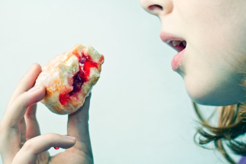 Young woman eating a jelly donut.